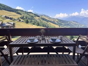 drewniany stół z dwoma kubkami na balkonie w obiekcie Résidence Valeriane - La Valériane 103 - Très beau 2 pièces avec vue dégagée sur la vallée MAE-6304 w mieście Valmorel +2 zdjęcia