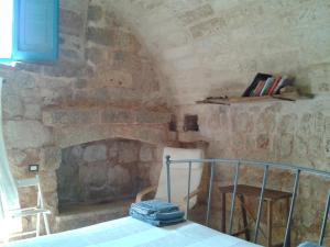 een kamer met een stenen open haard met een tafel en stoelen bij Trullo Nicola in Castrignano del Capo