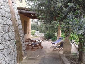 een patio met tafels en stoelen en een stenen muur bij Trullo Nicola in Castrignano del Capo