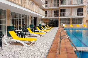 una piscina de hotel con sillas amarillas, mesas y sillas en Hotel Riutort en El Arenal
