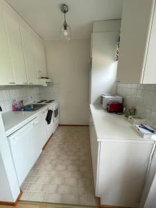 Una pequeña cocina con gabinetes blancos y un fregadero. en Annelis apartment, en Raseborg