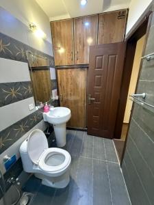 a bathroom with a toilet and a sink and a door at Staycation Apartments in Lahore