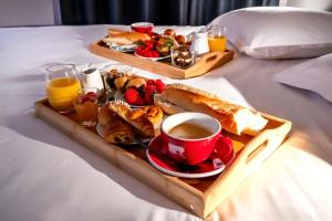 a tray of breakfast foods and a cup of coffee on a bed at Suite sous les toits 25m2 à 1mn du port de CASSIS in Cassis
