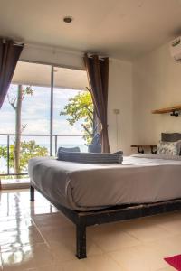 a large bed in a room with a large window at Cliff Cottage in Ko Chang