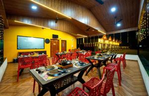a restaurant with tables and red chairs and a large screen at The Enchanted Nest By Privy Stays in Alibag