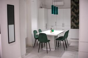 a kitchen with a white table and green chairs at Center Flat in Szeged