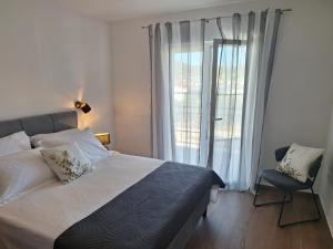 a bedroom with a bed and a chair and a window at Apartmani Jerka in Vinišće +57 photos