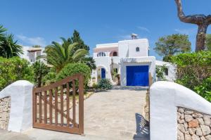 a gate leading to a white house with a blue door at Villa Cala Esmeralda in Cala d´Or