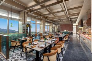 a restaurant with tables and chairs and windows at Hotel Indigo Nalati by IHG in Narat