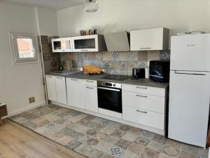 a kitchen with white cabinets and a white refrigerator at Saint Florent T2 Plein Centre in Saint-Florent +5 photos