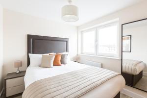 a white bedroom with a large bed and two windows at House of Fisher - Central Gate in Newbury