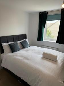 Un dormitorio con una gran cama blanca con ventana. en Diadem Comfort Suites, en Dartford