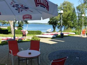a table and chairs under an umbrella next to the water at Biały Łabędź - Własne pomosty i kajaki in Kretowiny +31 photos