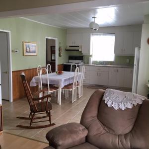 Maison l'héritage في لأنسي سانت جين: مطبخ وغرفة معيشة مع طاولة وكراسي