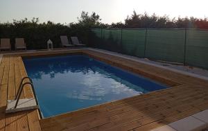 a swimming pool with a wooden deck and a fence at Ulivo Apartment in Ragusa