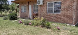 a brick house with a window and flowers in the yard at Casa Quinta San Miguel del Monte in San Miguel del Monte