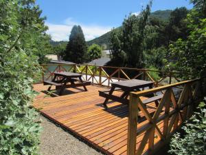 a wooden deck with two picnic tables on it at Apart Cascadas in San Martín de los Andes