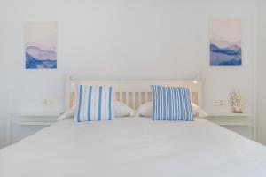 a white bed with two blue and white striped pillows at Playa de Guacimeta - Maresia in Playa Honda
