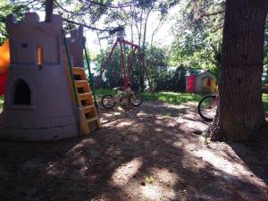 um parque infantil com um baloiço e uma bicicleta estacionada ao lado de uma árvore em Agriturismo Le Vergare em Offagna