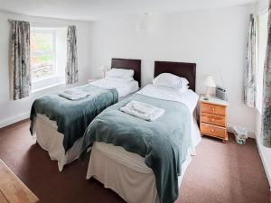 a bedroom with two beds and a dresser and a window at Lilac Cottage in Hawes
