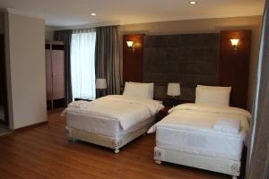 duas camas num quarto de hotel com lençóis brancos em Hotel Park Green em Poti