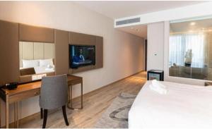 a hotel room with a bed and a desk and a tv at Panorama Nha Trang Sunlight Apartment in Nha Trang +5 photos