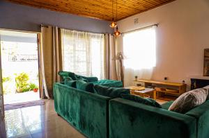 a living room with green couches in front of a window at Garden Villa Homestay in Arusha