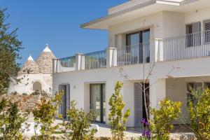 a white house with a balcony and trees at white moon holiday home in Ostuni