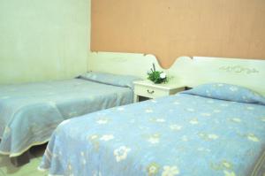 a room with two beds with blue sheets and a table at Hotel Metropolitan I in Irapuato
