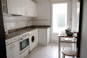 a white kitchen with a sink and a dishwasher at Bajo con jardin Costa Quebrada in Liencres
