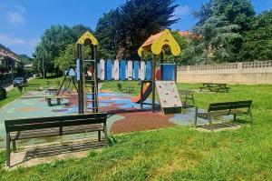 a playground in a park with benches and a play area at Bajo con jardin Costa Quebrada in Liencres