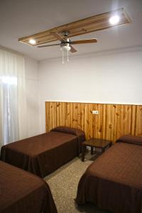 a room with two beds and a ceiling fan at Hostal Miranda in Blanes