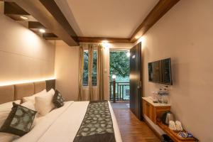 a bedroom with a bed and a tv and a window at Excel Hotels & Resorts Mall Road Nainital in Nainital
