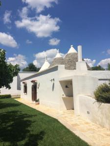 a white house with a grass yard at TRULLO del CAVALIERE delle GRAVINE in Castellaneta