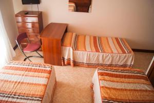a bedroom with two beds and a desk and a dresser at Hostal Hermanos Gutierrez in Monasterio de Rodilla