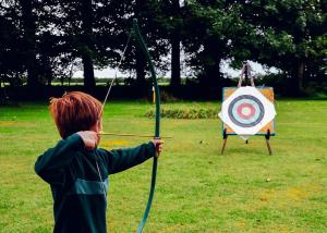 a young boy holding a arrow and a target at Woodovis Park in Tavistock