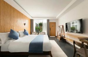 a hotel room with a bed and a flat screen tv at Tengchong Nan Su Gu Li Hot Spring EnjoyLife Family Resort (Tengyue Culture Plaza Branch) in Tengchong