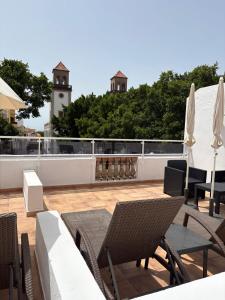 a patio with chairs and tables and a clock tower at Casas La Aldea Suites Plaza 3 in La Aldea de San Nicolas
