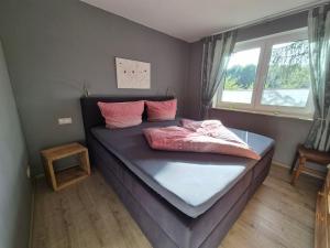 a bedroom with a bed with pink pillows on it at Rügen-Fewo 1380 in Natzevitz +2 photos