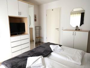 a white bedroom with a bed and a television at Residenz Strandkrone 02 in Kühlungsborn