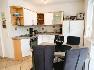 a kitchen with white cabinets and a table and chairs at Residenz Strandkrone 02 in Kühlungsborn