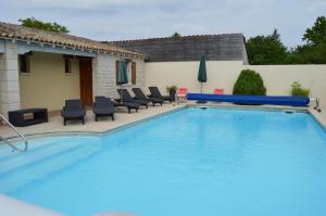 a swimming pool with lounge chairs next to a house at Les Chenets in Chenay