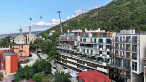 a city with buildings and a hill in the background at Castor & Pollux Hotel in Tbilisi City
