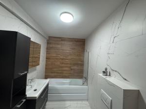 a white bathroom with a tub and a sink at City Vibe Apartment in Baia Mare