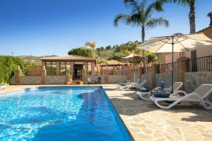 a swimming pool with lounge chairs and an umbrella at Villa Conmigo Bed & Breakfast in Alhaurín de la Torre