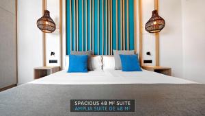 a bedroom with a large bed with blue pillows at HOVIMA Suites Costa Adeje in Adeje