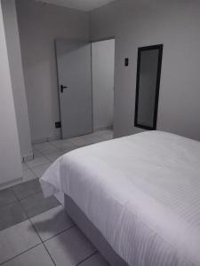 1 dormitorio con 1 cama blanca y 2 puertas correderas en Grace Villas 5, en East London 6 fotos más
