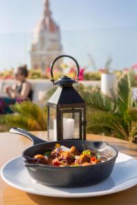 a pan of food on a plate next to a lantern at Movich Hotel Cartagena de Indias in Cartagena de Indias +42 photos