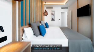 a bedroom with a large white bed with blue pillows at HOVIMA Suites Costa Adeje in Adeje