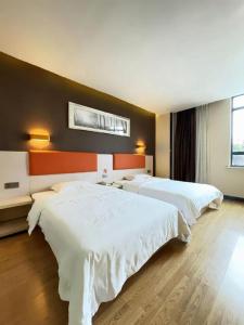 a hotel room with two beds and a wall at 7 Days Premium·Huanggang Walking Street in Fan-k'ou-chieh